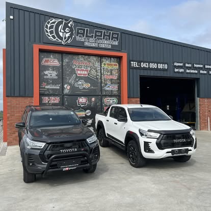 Two Toyota Hilux bakkies with bull bars parked at the Alpha shopfront